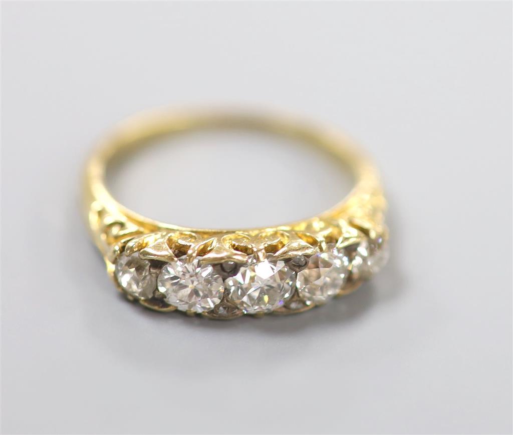 An early 20th century yellow metal and graduated five stone diamond set half hoop ring, size N, gross 3.6 grams.
